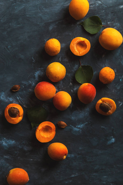 Ripe juicy orange apricots on blue concrete background, view from above. Copy space. - Photo, Image