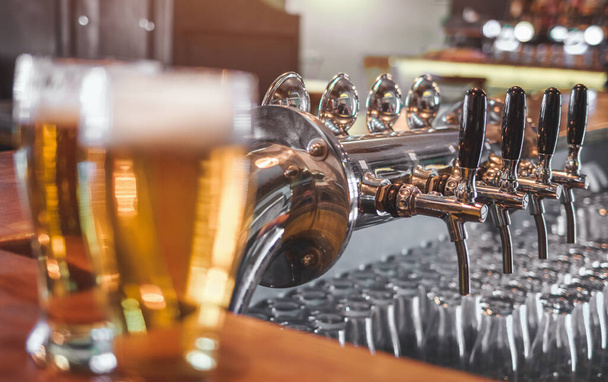 Two  Glasses of Beer on a bar table. Focus on Beer Tap. - Photo, Image