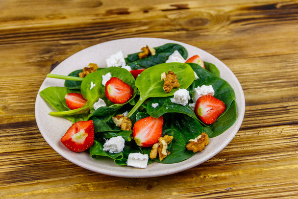 Frischer gesunder Salat mit Erdbeere, Spinat, Walnüssen und Feta-Käse auf Holztisch - Foto, Bild