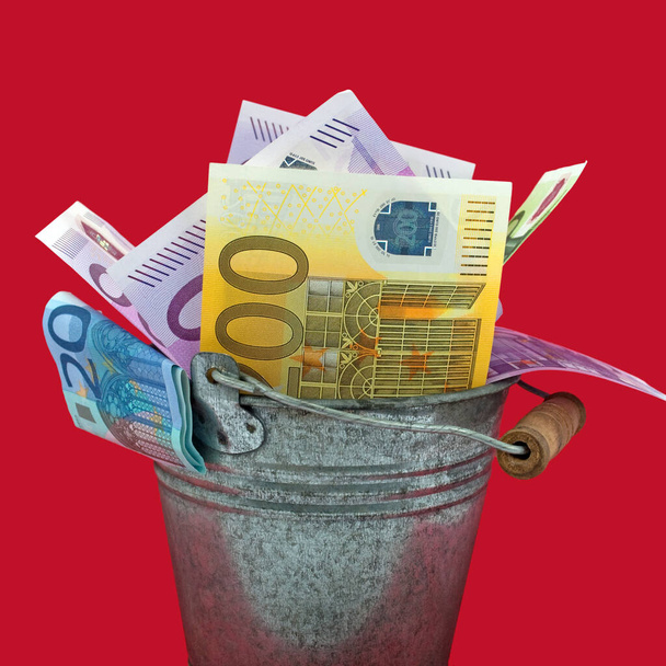 Banconote in euro in un secchio sullo sfondo rosso - Foto, immagini