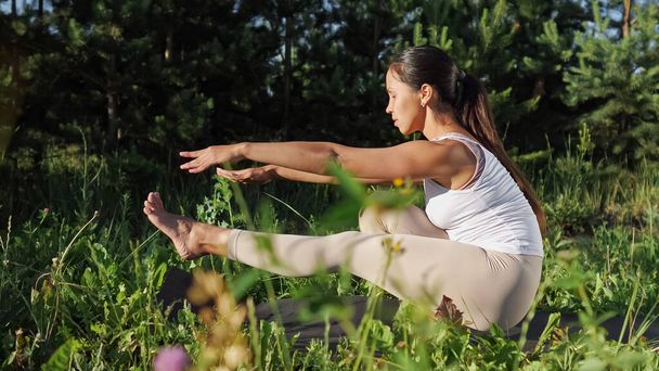 Vrouwelijke yogi op een gymmat. Camera beweging tussen gras - Foto, afbeelding