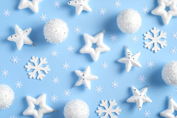 Composition de Noël. Motif composé de flocons de neige blancs, boules, étoiles, confettis sur fond bleu. Couché plat, vue du dessus. - Photo, image