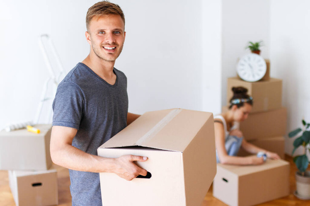 Moving day. Young man carrying cardboard box and smiling - Photo, Image