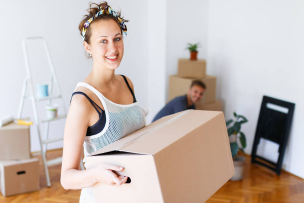 Stěhovací den. Mladá žena s kartonovou krabicí a úsměvem - Fotografie, Obrázek