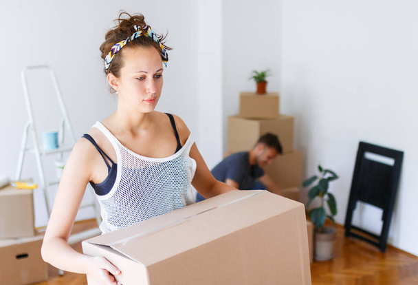 Moving out. Young woman carrying cardboard box felling tired - Photo, Image