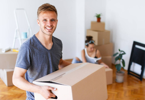 Moving day. Young man carrying cardboard box and smiling - Photo, Image