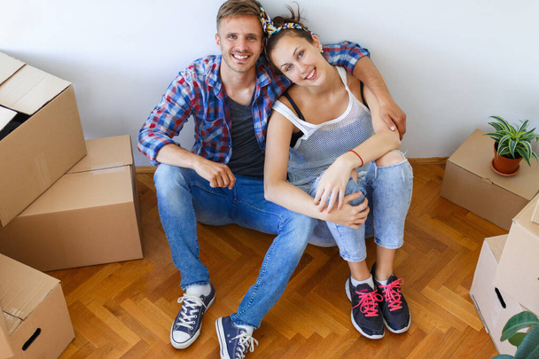 Emménager dans une nouvelle maison. Jeune couple amoureux assis sur le sol entouré de boîtes - Photo, image
