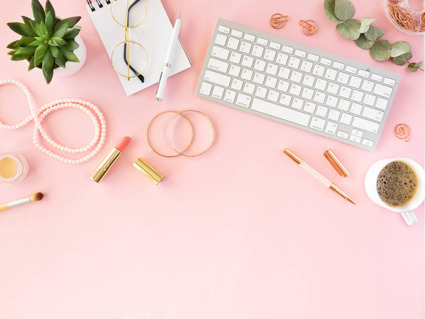 Feminine desktop fashion women flat lay. Top view accessories, cosmetic and jewelry, cup of coffee and keyboard on a pink background. Copy space - Photo, Image