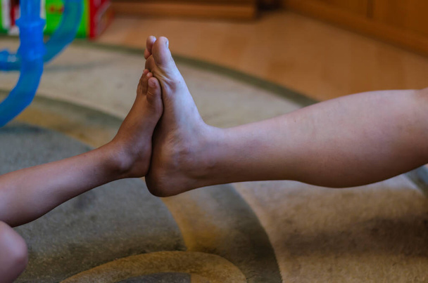 Dotykanie stóp dorosłej kobiety i chłopca z przedszkola. Dziecko i matka porównują rozmiar nóg spoczywających na stopach. Szczęśliwego życia. Skupienie selektywne. - Zdjęcie, obraz