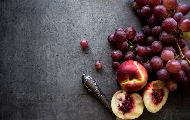 Frische Früchte auf grauem Hintergrund mit Kopierraum. Foto von oben mit saftigen Trauben, Birnen und Nektarinen. Konzept der gesunden Ernährung.  - Foto, Bild