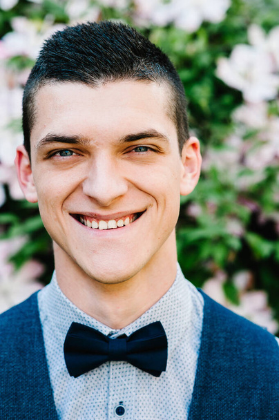Whole face close up portrait of happy man. smiling looking at camera. Charming, confident, serious and handsome. young person isolated on background nature. A man with a butterfly in a suit. - Photo, image