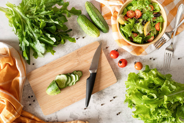 Concetto di cibo sano. Vista dall'alto di fare insalata di verdure con tagliere, ciotola di insalata e verdure biologiche fresche - Foto, immagini