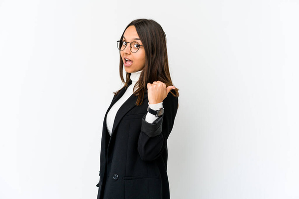 Young mixed race business woman isolated on white background points with thumb finger away, laughing and carefree. - Fotó, kép
