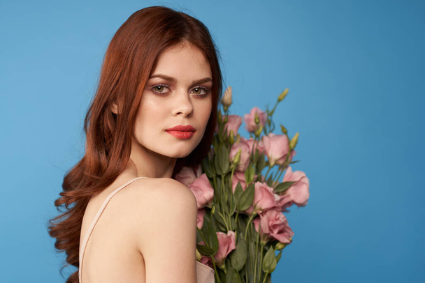 Beautiful woman with a bouquet of pink flowers on a blue background spring model  - Photo, Image