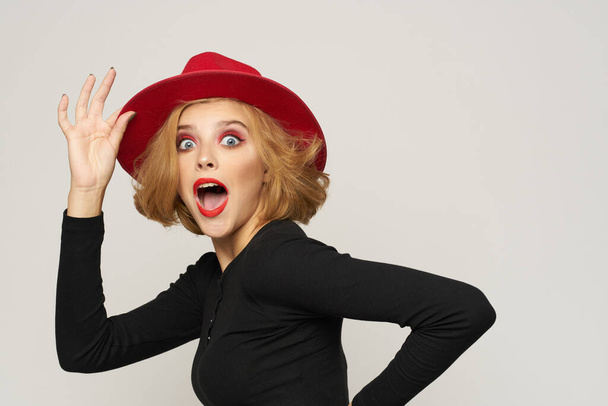 Fashionable woman in red hat black blouse red lips cropped view light background emotions - Photo, Image