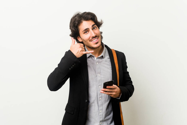 Young business man holding a phone showing a mobile phone call gesture with fingers. - Photo, image