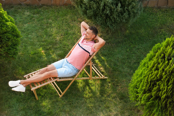 Happy man resting in deck chair outdoors, above view - Fotografie, Obrázek