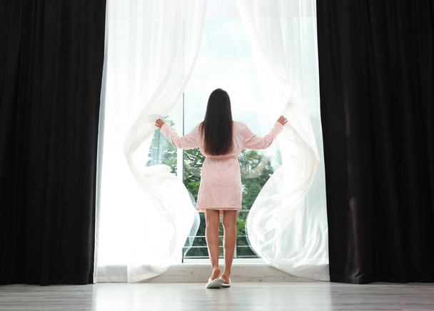 Young woman opening curtains at home. Good morning - Fotoğraf, Görsel