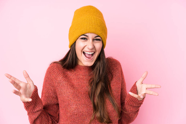 Young caucasian woman wearing a wool cap isolated receiving a pleasant surprise, excited and raising hands. - Photo, image