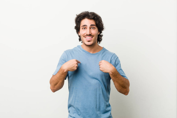 Young handsome man against a white background surprised pointing with finger, smiling broadly. - Photo, Image