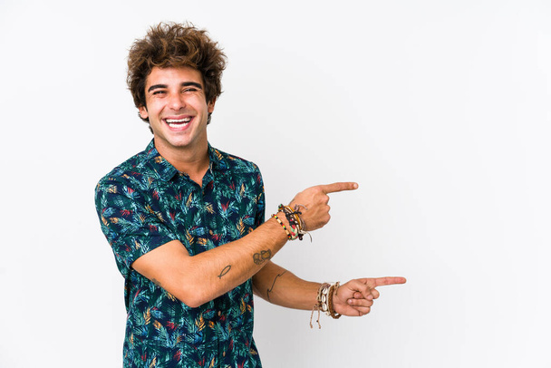 Молодой кавказский мужчина в цветочной футболке, возбужденный, указывая указательными пальцами. - Фото, изображение