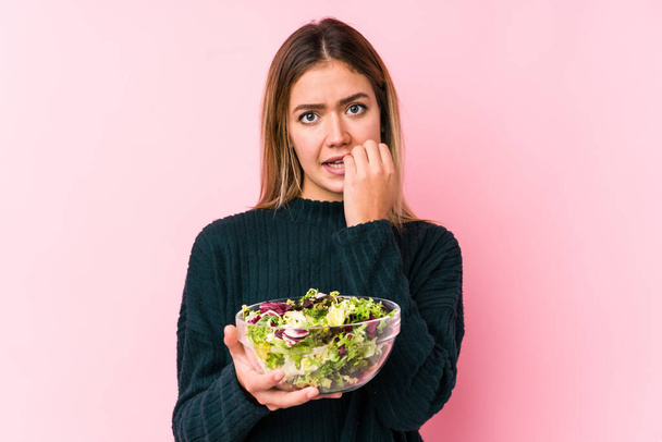 Elinde salata tutan beyaz bir kadın. Tırnaklarını yiyor. Gergin ve endişeli.. - Fotoğraf, Görsel