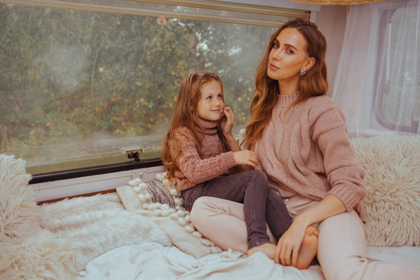 Boldog család - anya és kislánya pihentető ölelés és szórakozás vidéken belül fehér skandináv rusztikus lakókocsi van belső. A belföldi turizmus fogalma  - Fotó, kép