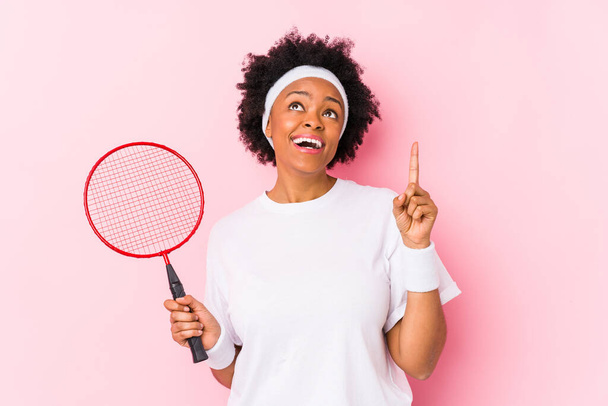 Badminton oynayan genç Afrikalı Amerikalı kadın ağzı açık bir şekilde üst tarafı işaret ediyor.. - Fotoğraf, Görsel