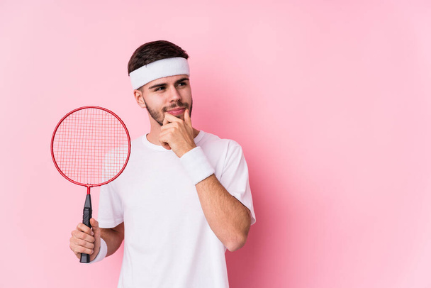 Badminton oynayan beyaz bir adam şüpheli ve şüpheci bir ifadeyle yanlamasına bakıyor.. - Fotoğraf, Görsel