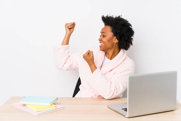 Mujer afroamericana de mediana edad que trabaja en casa aislada levantando puño después de una victoria, concepto ganador. - Foto, Imagen