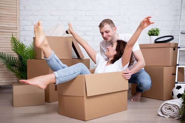 счастливая пара веселится с картонными коробками в своем новом доме или квартире - Фото, изображение