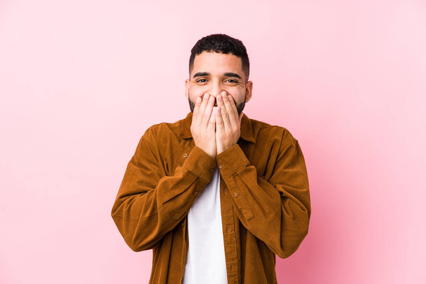 Young latin man against a pink background isolated laughing about something, covering mouth with hands. - Фото, зображення