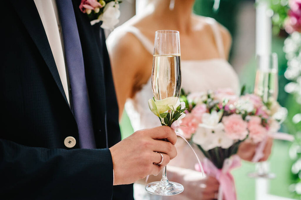 The hand groom's holds a glass of champagne on the background of the bride. Wedding ceremony. - Foto, Bild