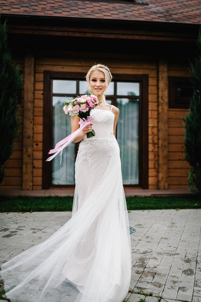 Jonge mooie bruid in een elegante jurk met een boeket dansen en draaien, spinnen op een bruiloft. - Foto, afbeelding