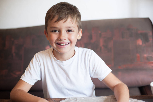  Euroopan näköinen poika pitelee maitolasia huulensa päällä ja maitomaisia viiksiä ja nauraa. terveellinen aamiainen. Onnellinen lapsi - Valokuva, kuva