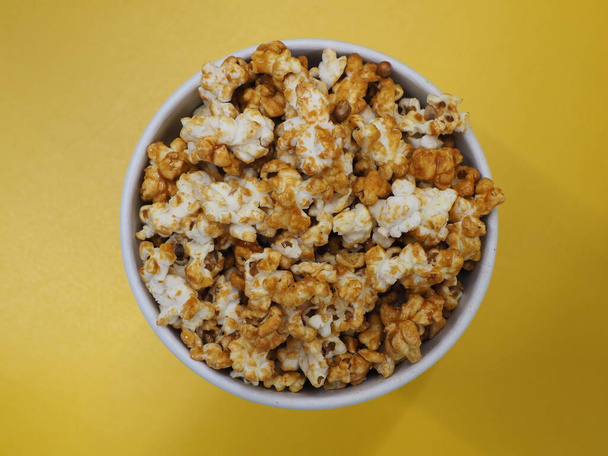 Popcorn in einem Pappbecher auf gelbem Hintergrund - Foto, Bild