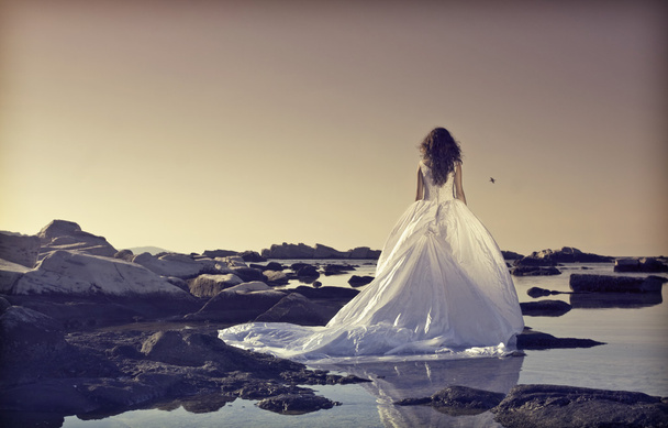 Young bride standing on a cliff at the sea - Φωτογραφία, εικόνα