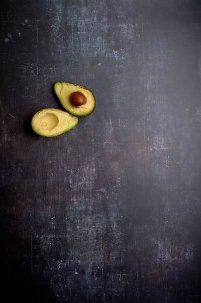 a set of cut and uncut avocados, on a dark, black, cement, metallic, marble and stone background - Foto, Imagem