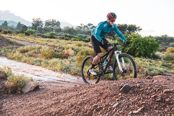 mountain biker cycling on a dirt track during autumn, fall and winter seasons - Photo, Image