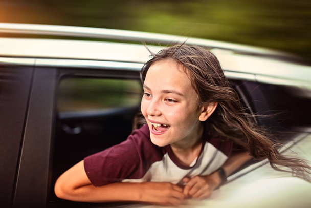 smiling brunette teenage girl is driving the car - Фото, изображение