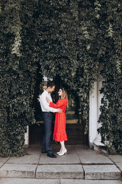 Piękna para, dziewczyna w czerwonej sukience i facet w białej koszuli, spacerują po parku w naturze - Zdjęcie, obraz