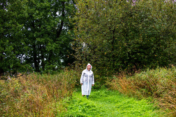 woman in a raincoat in the woods for a walk - Фото, изображение