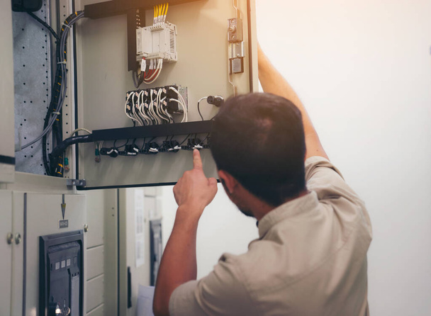Elektrotechnicus controleert spanning en test bij de Power Distribution Cabinet in de controlekamer, preventief onderhoud Jaarlijks - Foto, afbeelding