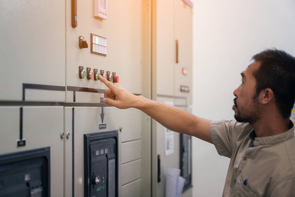 Engenheiro elétrico homem de verificação de tensão e teste no armário de distribuição de energia na sala de controle, manutenção preventiva anual - Foto, Imagem