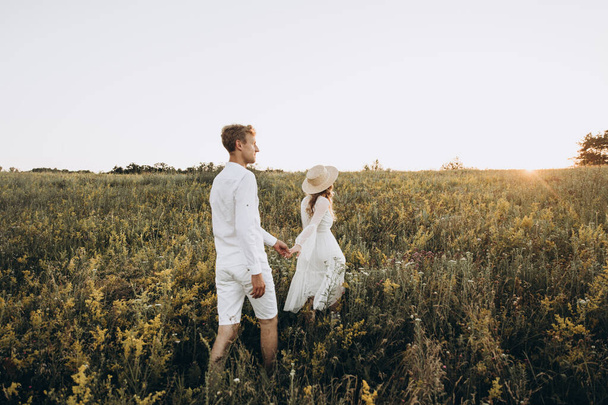 Couple in white are walking on green nature at sunset in summer - Fotoğraf, Görsel
