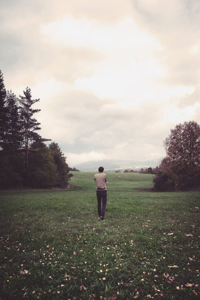 man staat alleen op het weitje, verticaal beeld van eenzame man zich zorgen maken over zijn problemen op een leeg verlaten landschap - Foto, afbeelding