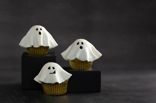 Cupcakes fantasma fondant Halloween em pódios pretos. Halloween festa comida ideia. - Foto, Imagem