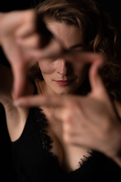 Portrét holé dívky, která se dívá skrz prsty přímo do kamery - Fotografie, Obrázek