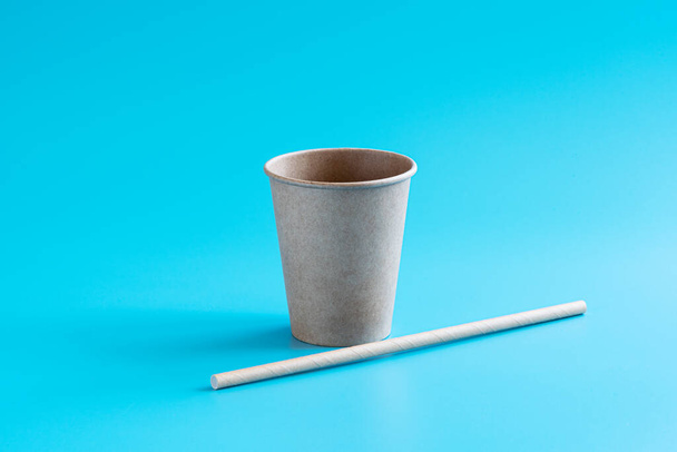 Переработанная бумажная чашка и питьевая солома на синем фоне. Экологичная биоразлагаемая посуда для питья. Концепция нулевых отходов. Минимальный стиль. Копирование пространства - Фото, изображение
