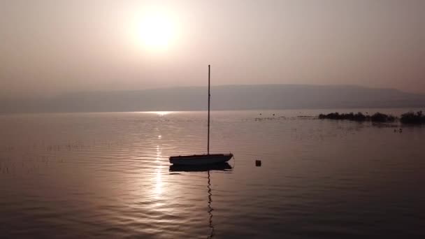 Salida del sol sobre el lago. Barco flotando en el agua tranquila bajo increíble puesta de sol. - Imágenes, Vídeo